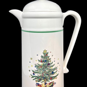 Puede incluir: Cafetera térmica de cerámica blanca con un borde verde y un diseño de árbol de Navidad. El árbol está decorado con adornos, estrellas y regalos.