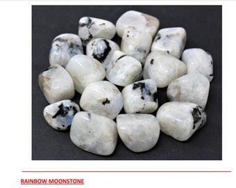May include: A collection of smooth, white rainbow moonstone tumbled stones with black inclusions. The stones are arranged in a circle on a black background.