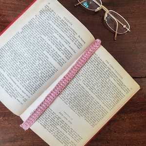 Op de afbeelding: Een open boek met een roze gehaakt bladwijzer. Het boek is getiteld "Villette" en "The Long Vacation". Een bril met een gouden montuur ligt op het boek.