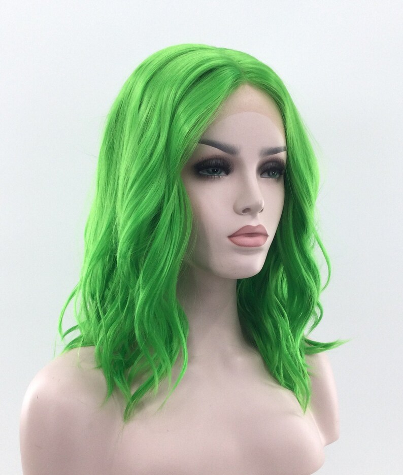 May include: A bright green, wavy synthetic wig with a lace front. The wig is styled in a shoulder-length bob.