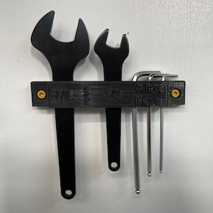 May include: A black metal tool organizer with a label that reads "Allen Keys" and includes markings for 7/8, 1/2, and 1/4 inch wrenches. The organizer holds a set of Allen wrenches.