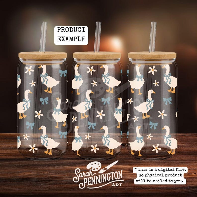 May include: Three glass tumblers with bamboo lids and straws. The tumblers feature a pattern of white geese with blue bows and white flowers on a dark background. The text "PRODUCT EXAMPLE" is visible.