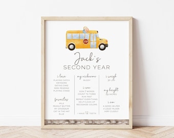 May include: A framed print featuring a yellow school bus illustration. The print includes the text "Jack's SECOND YEAR" and personal details such as weight (30 lbs), height (29 inches), and favorite things. The bottom border has a road design.
