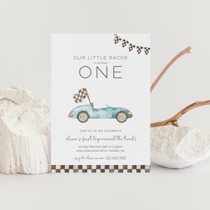 Puede incluir: Una tarjeta blanca con una ilustración de un coche de carreras azul y blanco y el texto "Our Little Racer is turning ONE". La tarjeta también incluye el texto "Join us as we celebrate Oliver's first lap around the track!" y los detalles del evento.