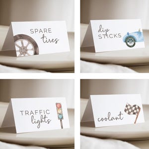 May include: Four white tent cards with watercolour illustrations and text. The cards feature a tyre with "spare tyres", a blue car with "dip sticks", a traffic light with "traffic lights", and a checkered flag with "coolant".