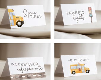 Può includere: Quattro biglietti bianchi con illustrazioni ad acquerello e testo. Un biglietto mostra un autobus scolastico giallo e le parole "Spare Tires". Un altro mostra un semaforo e le parole "Traffic Lights". Un terzo biglietto recita "Passenger Refreshments". L'ultimo biglietto mostra un autobus scolastico e recita "-Bus Stop-".
