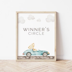 May include: A framed print with a watercolor illustration of a blue car driving on a road with a gold trophy in the driver's seat. The text "WINNER'S CIRCLE" is above the car.