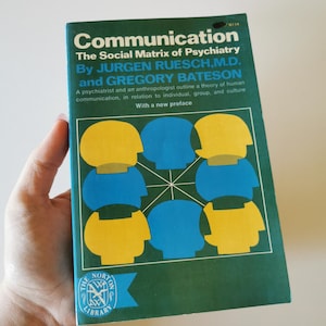 Peut inclure: Un livre de poche vintage intitulé "Communication" avec une couverture verte. La couverture présente un graphique de silhouettes de têtes bleues et jaunes interconnectées. Le titre du livre et les noms des auteurs sont en texte blanc. Le logo Norton Library est en bas.