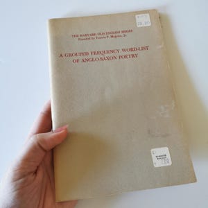 May include: A vintage book titled "A Grouped Frequency Word-List of Anglo-Saxon Poetry" from the Harvard Old English Series. The cover is a light tan color with red text. The book has a price tag of $2.20.