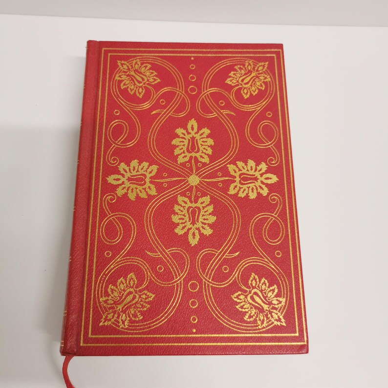 May include: A red hardcover book with a gold floral design on the cover.