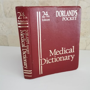 Op de afbeelding: Een bordeauxrode "Dorland's Pocket Medical Dictionary", 24e editie. De titel en het editienummer staan in witte letters. De rug toont de titel en uitgever, Saunders, in gouden letters.
