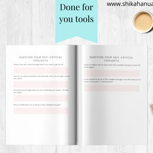 May include: An open notebook with prompts for self-reflection, titled "Question Your Self-Critical Thoughts." Includes questions about identifying and managing negative thoughts. A cup of coffee and a pen are also visible.