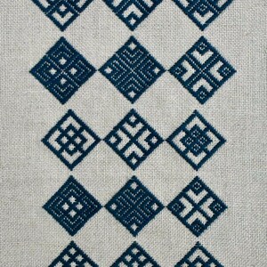 May include: A piece of light beige linen fabric featuring fifteen dark blue embroidered diamond-shaped motifs arranged in a grid of five rows and three columns. Each diamond contains a unique geometric pattern made of straight stitched lines.