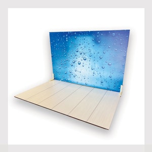 May include: A white wooden floor with a blue backdrop featuring a water droplet pattern. The backdrop is attached to the floor with white corner brackets.