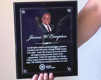 May include: A black framed plaque with a portrait of James W. Compton, a civil rights activist. Text on the plaque details his service as President and CEO of the Chicago Urban League from 1978-2006. The Chicago Urban League logo is at the bottom.