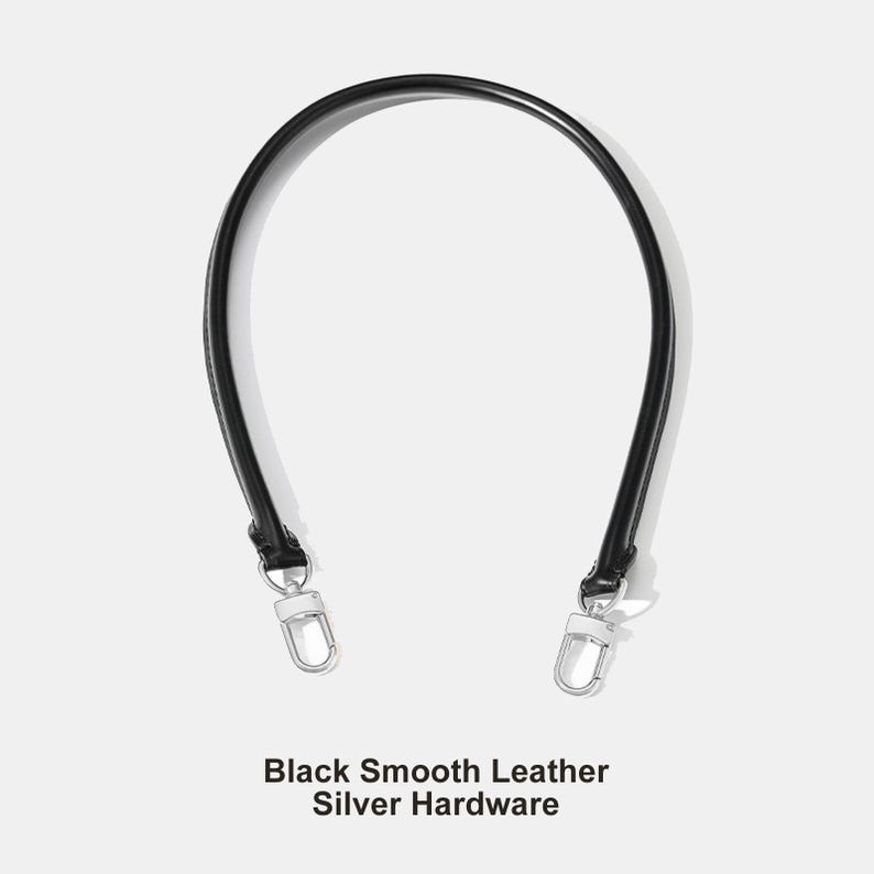 May include: A black smooth leather handbag strap with silver hardware. The strap is curved and has a sleek, minimalist design. The text "Black Smooth Leather Silver Hardware" is at the bottom of the image.