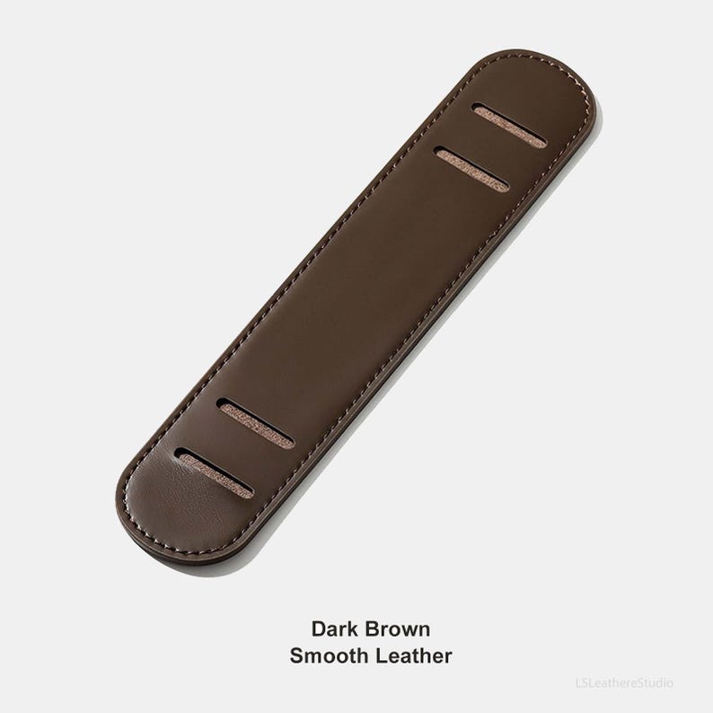 May include: A dark brown, smooth leather guitar strap pad. The pad has three rectangular slots and rounded ends. The text "Dark Brown Smooth Leather" is at the bottom of the image.