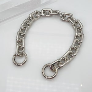 May include: A silver chain necklace with a large, chunky link design. The chain has two circular clasps.