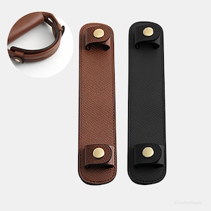 May include: Two leather bag handle wraps, one brown and one black, with gold-coloured snap closures. A close-up of a brown handle wrap is in the upper left corner. The wraps are rectangular and have a textured surface.