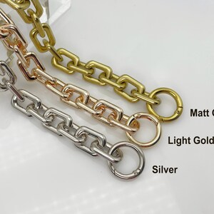 May include: Three chain links in different finishes: silver, light gold, and matt gold. Each chain has a round ring at the end.