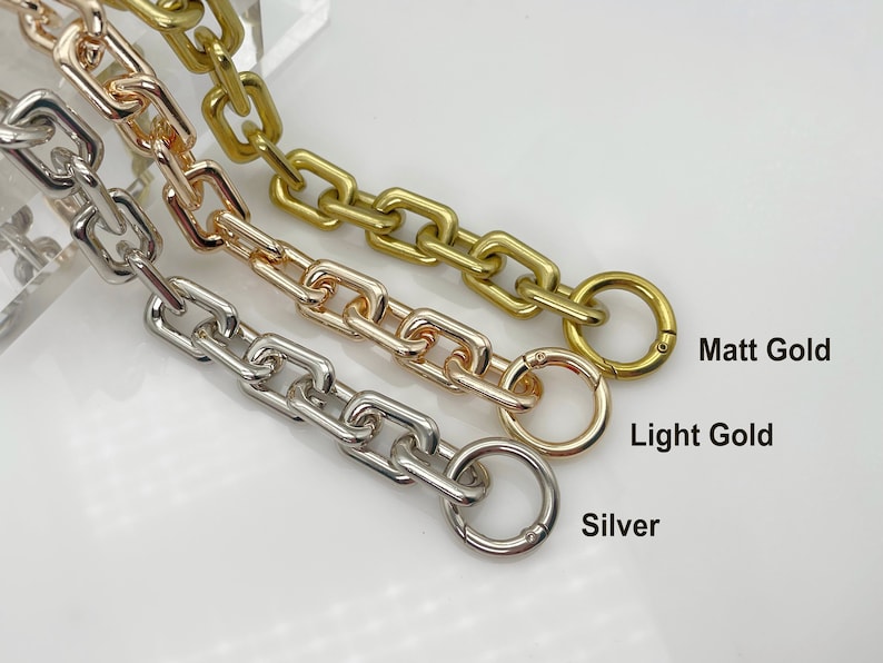May include: Three chain links in different finishes: silver, light gold, and matt gold. Each chain has a round ring at the end.