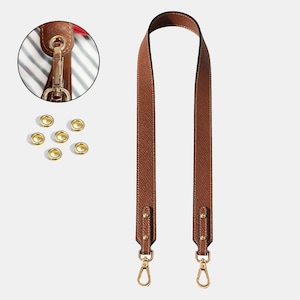 May include: A brown leather bag strap with gold-colored hardware, including clasps and rivets. The strap is shown with a close-up of the attachment hardware and several gold eyelets. The strap is designed for use with a handbag or purse.