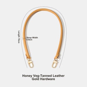 May include: Honey-colored, veg-tanned leather handbag handle with gold-colored hardware. The handle is 70cm long and 0.9cm wide. The text on the image reads: Honey Veg-Tanned Leather, Gold Hardware.
