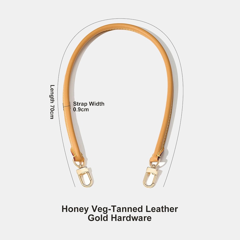 May include: Honey-colored, veg-tanned leather handbag handle with gold-colored hardware. The handle is 70cm long and 0.9cm wide. The text on the image reads: Honey Veg-Tanned Leather, Gold Hardware.