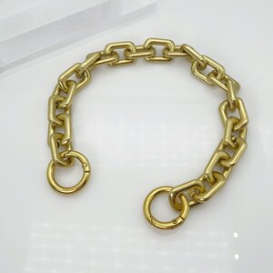May include: A gold chain with a large, chunky link design. The chain has a clasp on one end and a ring on the other.