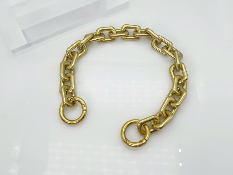 May include: A gold chain with a large, chunky link design. The chain has a clasp on one end and a ring on the other.