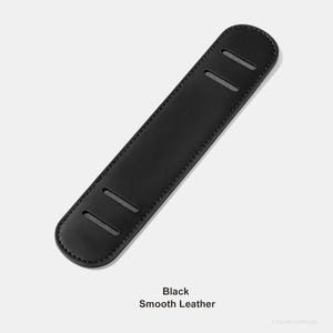 May include: A black, smooth leather shoulder pad with three rectangular slots. The text "Black Smooth Leather" is printed at the bottom of the image. The pad is designed to provide comfort and support.