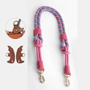 May include: A pink and blue patterned rope handbag strap with pink leather accents and gold-colored clasps. The strap is designed for easy attachment to a purse or bag. Includes close-up details of the bag attachment.