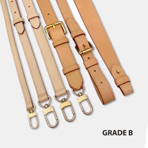 Könnte beinhalten: Verschiedene Lederriemen für Taschen in Beige- und Brauntönen. Die Riemen sind mit goldfarbenen Metallbeschlägen, einschließlich Schnallen und Verschlüssen, versehen. Das Bild enthält den Text "GRADE B".