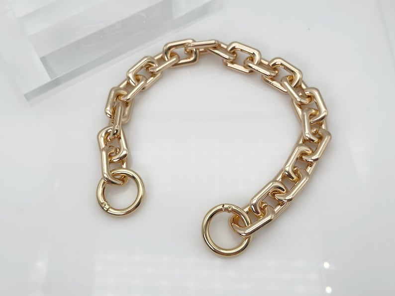 May include: A gold chain bracelet with a chunky link design and two circular clasps.