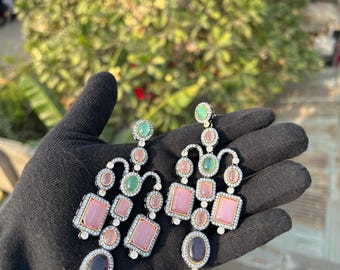 Può includere: Un paio di orecchini pendenti con pietre preziose rosa, verdi e nere. Gli orecchini sono in argento e hanno un design in stile chandelier.