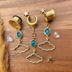 May include: Three gold ear gauges with dangling charms. Each charm features a green gemstone, a gold cloud, and a gold star.