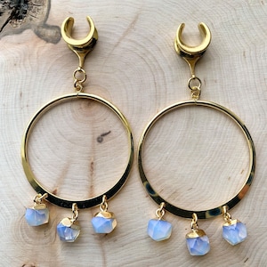 May include: Gold hoop earrings with a dangling crescent moon charm and three iridescent opal stones.
