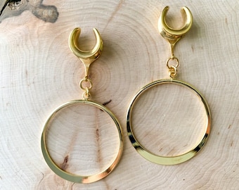 May include: A pair of gold-toned hoop earrings with a crescent moon-shaped dangle. The hoops are thick and have a smooth, polished finish.