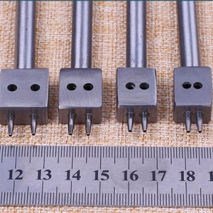 May include: Four silver leather hole punch tools with three prongs each. The tools are lined up in a row and are numbered 11 through 19 on a ruler.