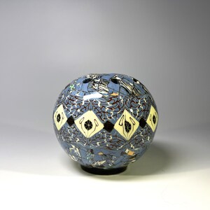 May include: A blue and white ceramic sphere vase with a geometric pattern. The vase has a series of small holes around the top.
