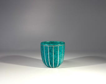 May include: A teal blue ceramic bowl with silver stripes around the exterior.