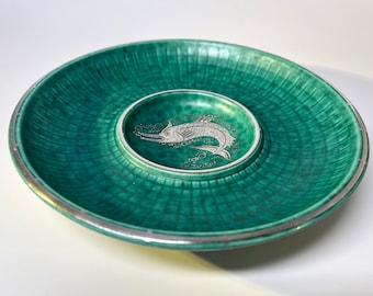 May include: A green ceramic serving dish with a silver rim and a smaller, centered dish featuring a silver fish design.