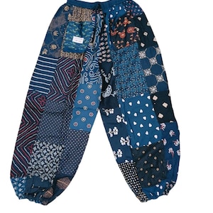 Könnte beinhalten: Blaue Patchwork-Hose mit Kordelzugbund und elastischen Bündchen. Die Hose besteht aus verschiedenen Stoffen mit verschiedenen Mustern, darunter Blumen, geometrische Muster und Paisley.