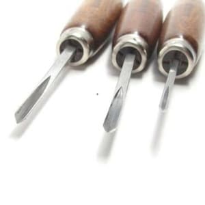 May include: Three wood handled carving tools with metal blades. The blades are sharpened to a point.