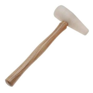 May include: A white rubber mallet with a wooden handle. The mallet is used for striking surfaces without damaging them.