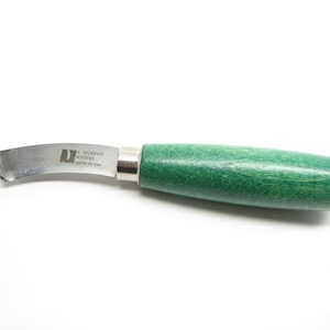 May include: A curved, stainless steel paring knife with a green wooden handle. The knife is labeled "E. Murphy Knives Made in USA".