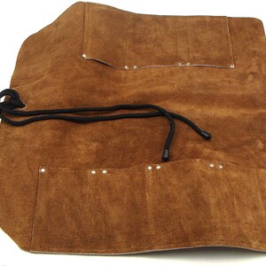 May include: Brown leather tool roll with multiple pockets and a drawstring closure. The roll is unrolled and shows the pockets inside.