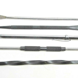 May include: Set of five metal tools with different tips, including a flat chisel, a pointed chisel, a bent tool, and two straight tools. The tools are silver and black.