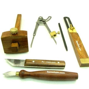 May include: A set of woodworking tools including a marking gauge, a compass, a marking knife, and two chisels. The tools are made of wood and metal and have a brass finish.