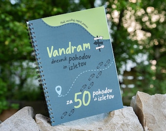 May include: A spiral-bound notebook with a blue and light green cover featuring the text "Vandram dnevnik pohodov in izletov" and "za 50 pohodov ali izletov," along with a graphic of a dashed path, footprints, a location pin, and signposts.